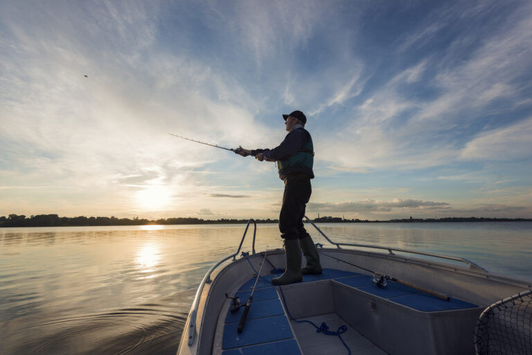 a photo of a fisherman on a boat casting his line