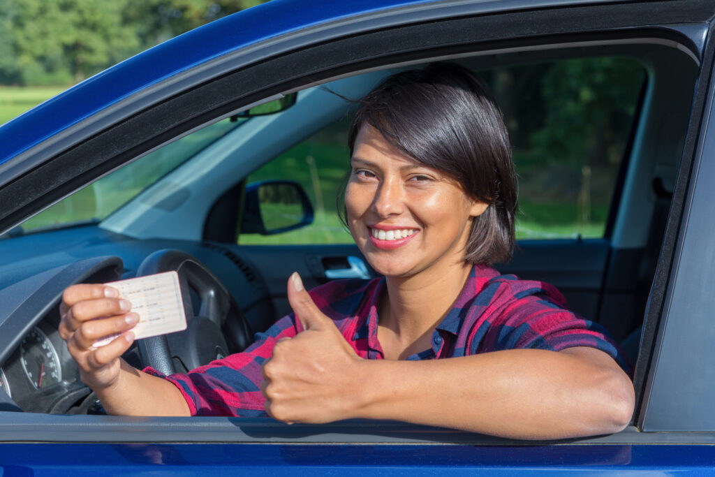a young woman showing her drivers license while sitting in her car