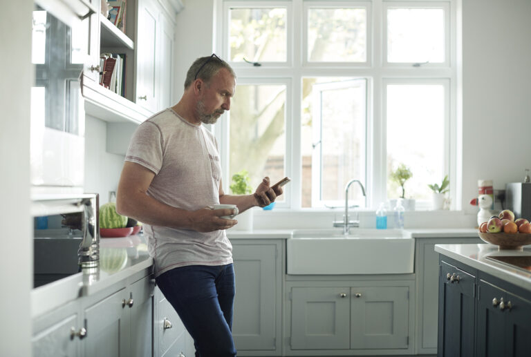 a man in his kitchen scrolling on his phone