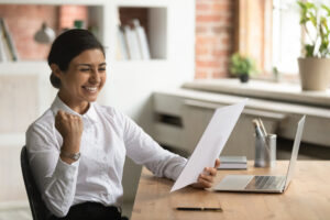 overjoyed smiling Indian businesswoman reading good news in a letter
