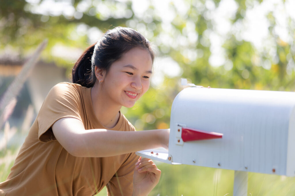 a photo of a woman looking for a letter in her mailbox
