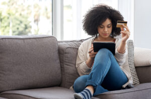 a photo of a young woman shopping online while sitting on her sofa at home