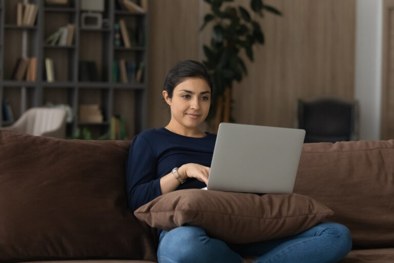 Indian woman relaxing on the couch with her laptop